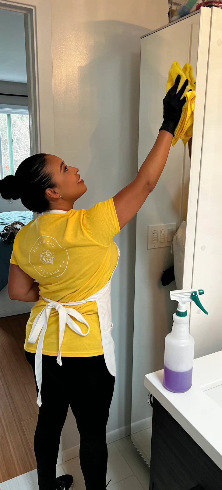 Buttercup cleaner wiping the top of bathroom cabinetry